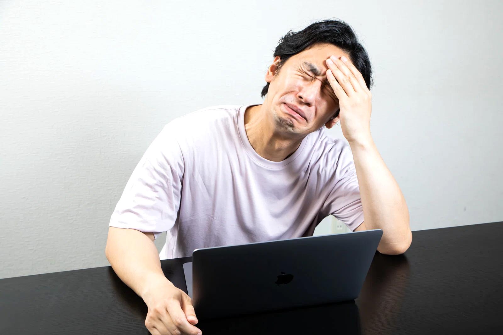 疲れた表情で夜遅くまで起きている人の生活イメージ