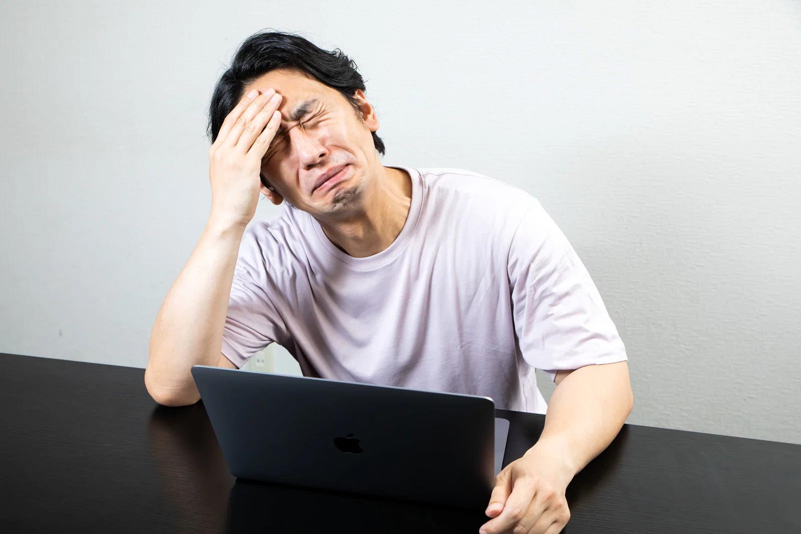 50代の男性が疲れた表情で頭を抱えストレスを感じている様子