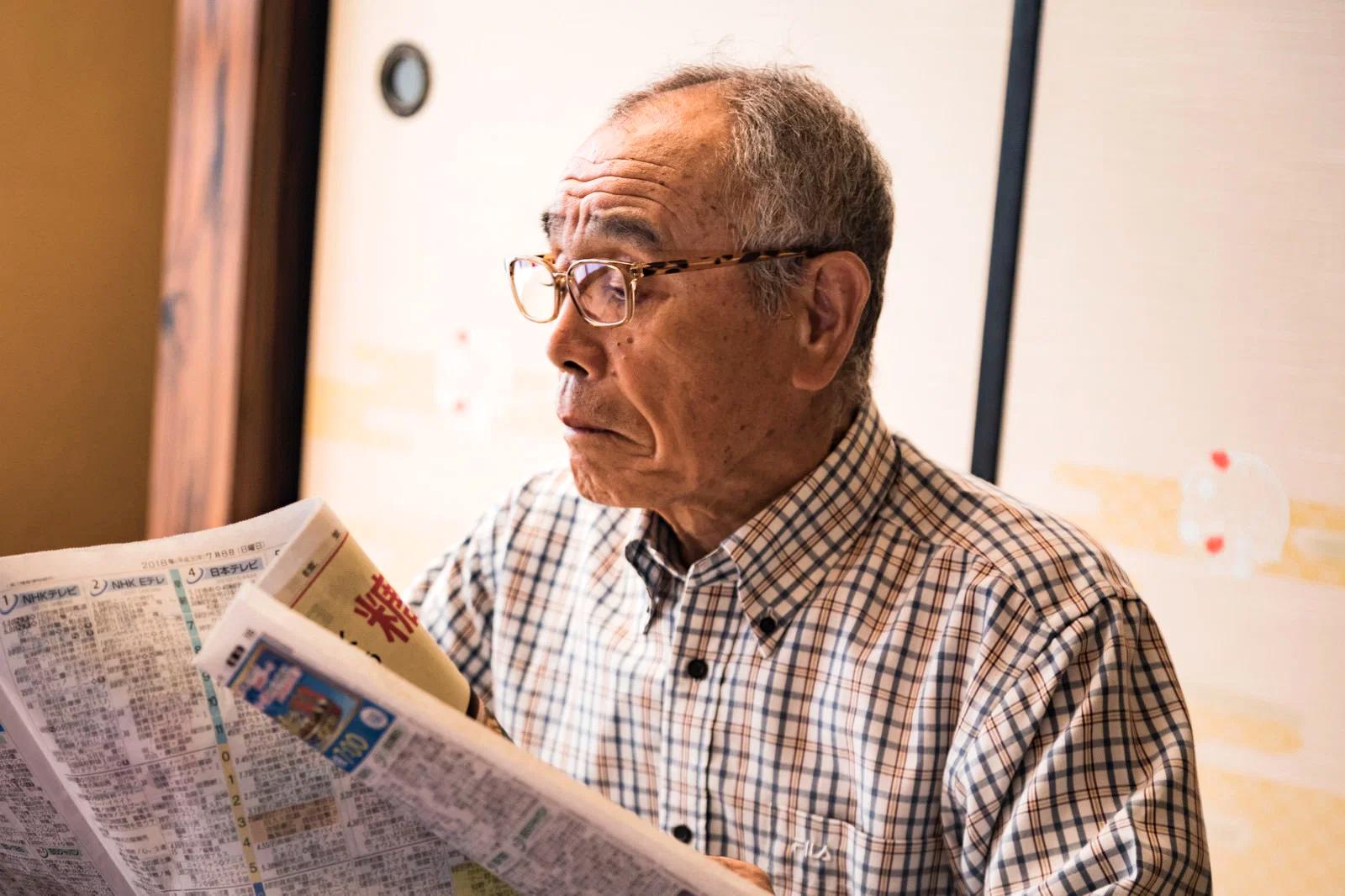 80代の高齢者が新聞を読む際に目を細めている様子と視力変化のイメージ