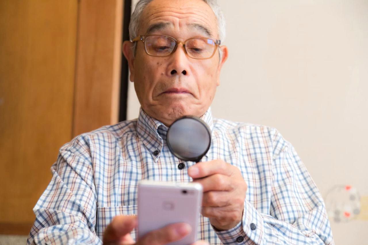 スマートフォンの設定画面を確認しながら個人情報を守る高齢者のイメージ
