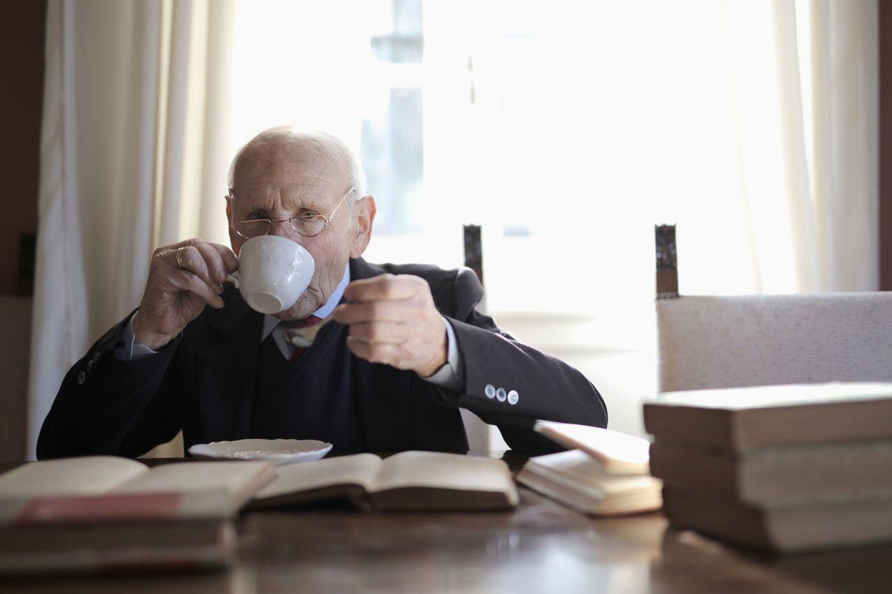 70代の高齢者がコーヒーカップを手に頻尿や脱水を心配する穏やかな表情