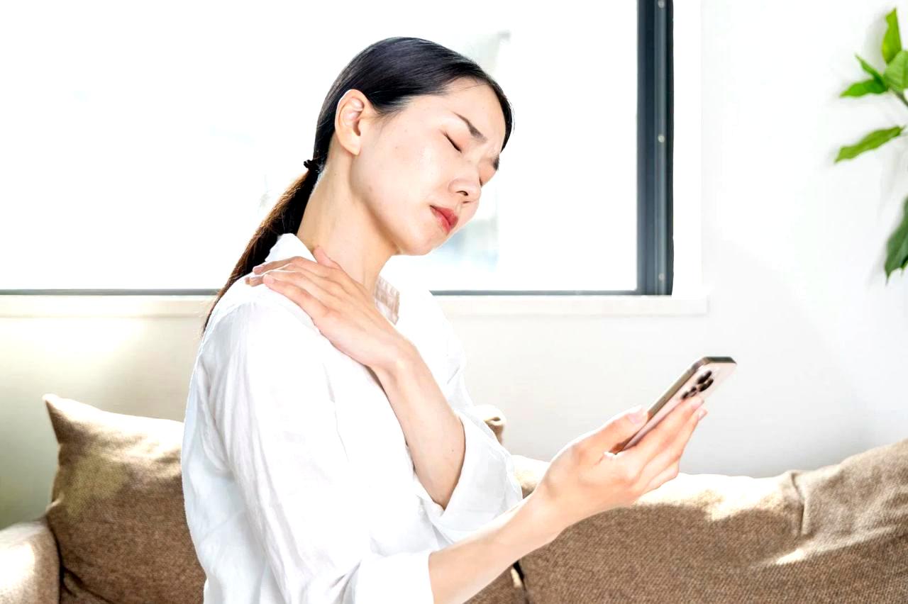 スマホを見る姿勢で首に負担をかける男性