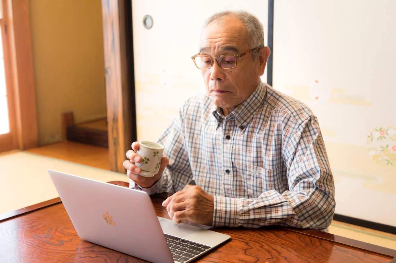スマートフォンに向かって話しかける穏やかな表情の高齢者