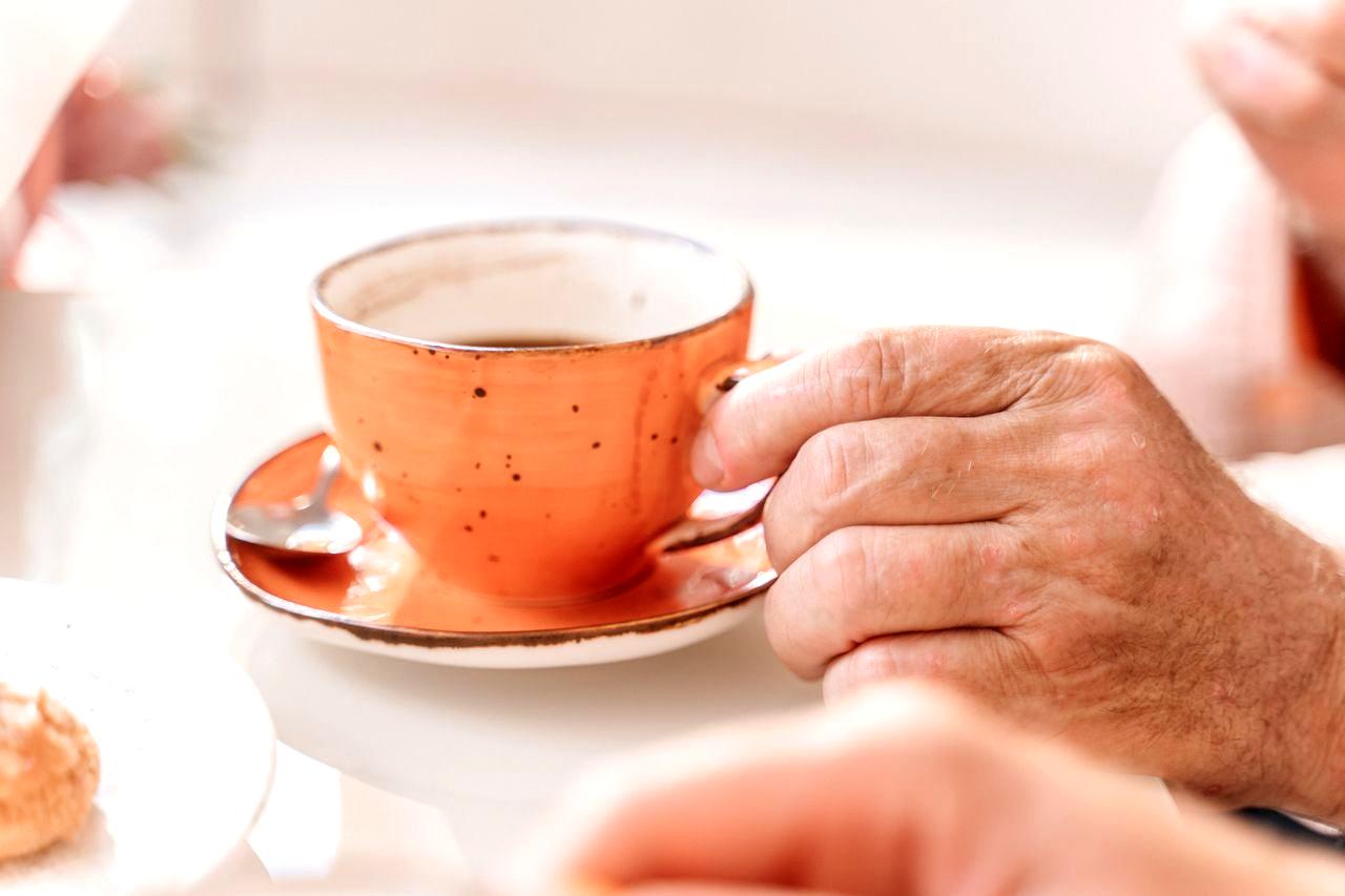 シニア男性がコーヒーを飲みながら健康への影響を考えている様子