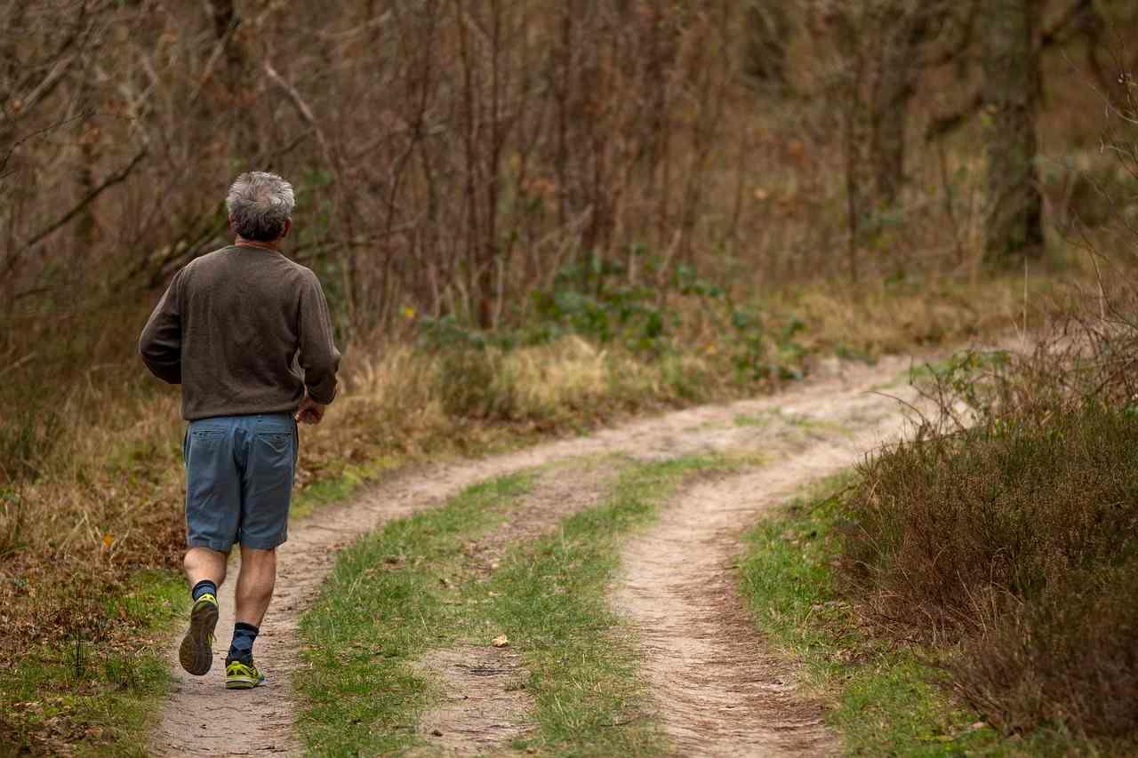 お腹に軽く手を当てながら歩く50代の女性。お腹周りを意識したウォーキング