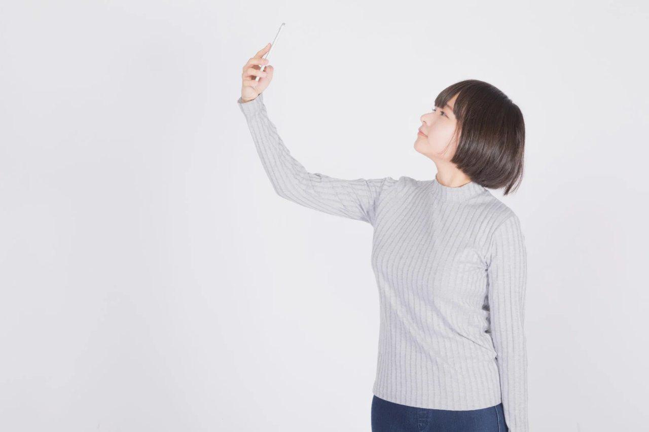自宅のリビングでスマホのピラティス動画を見ながら運動する女性