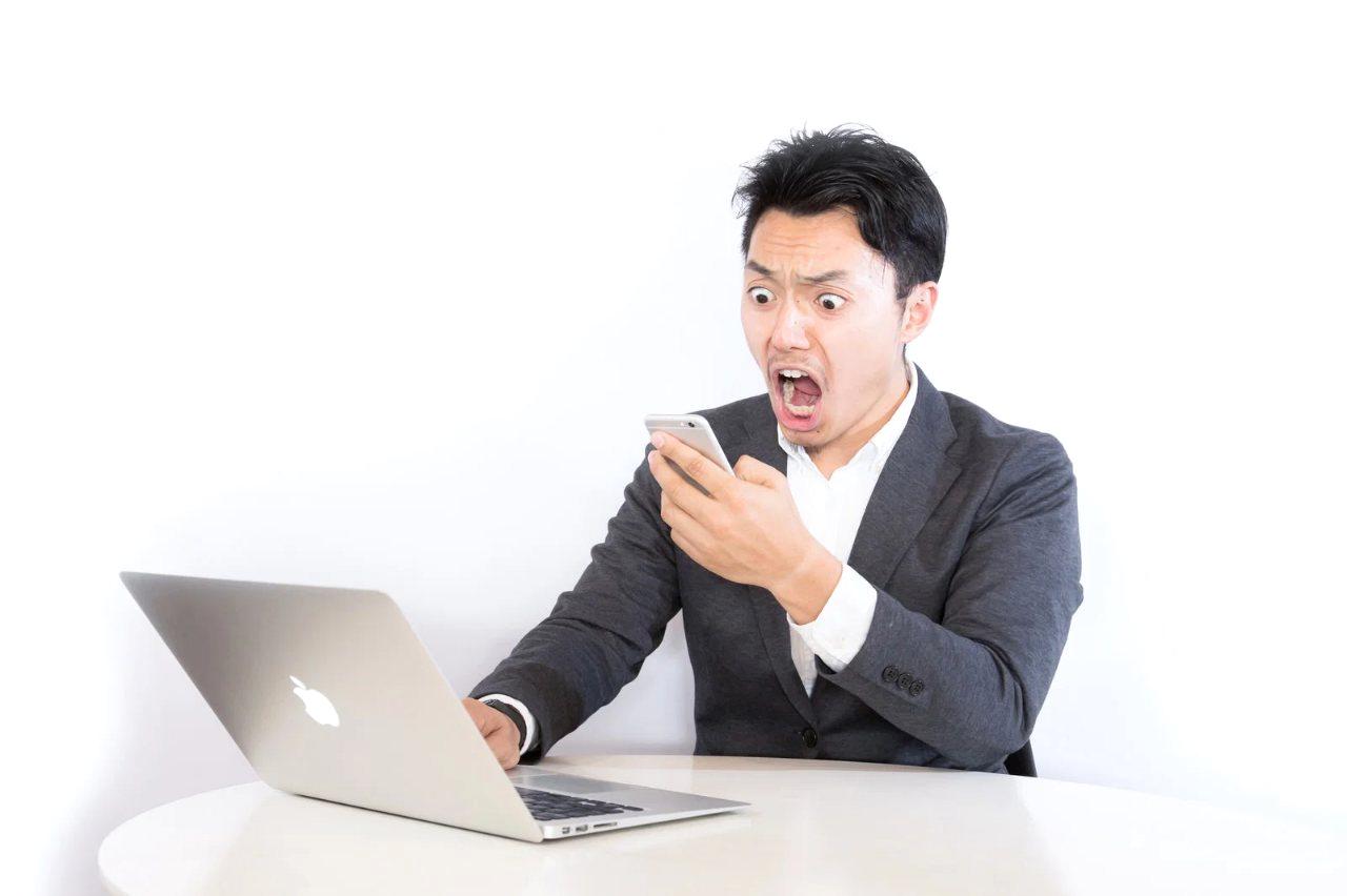 自宅のソファでスマホを持ち、楽しそうにビデオ通話をする高齢者