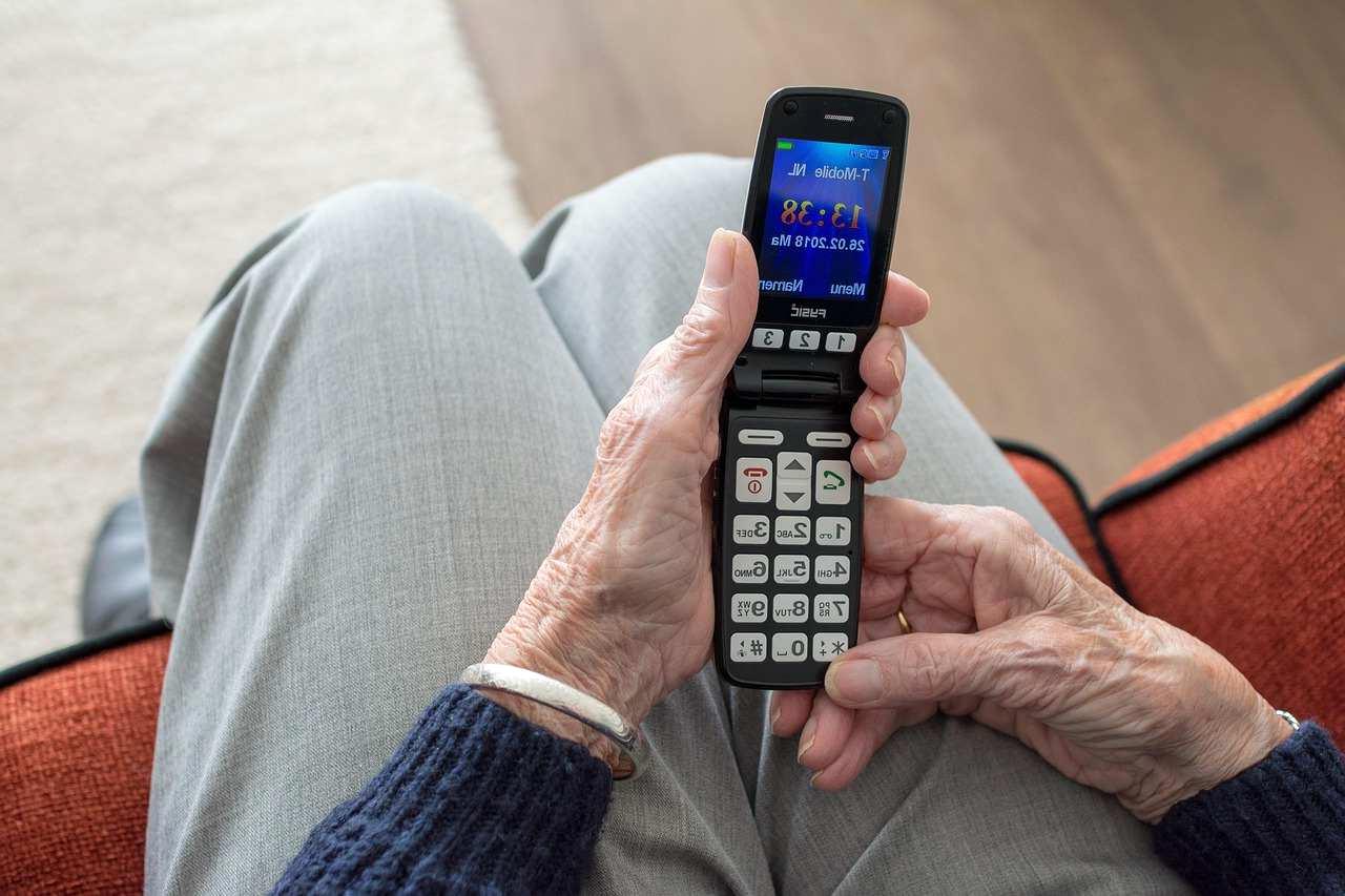 70代のシニア男性がスマホを見ながら、警戒心を持って怪しいメールを確認している様子