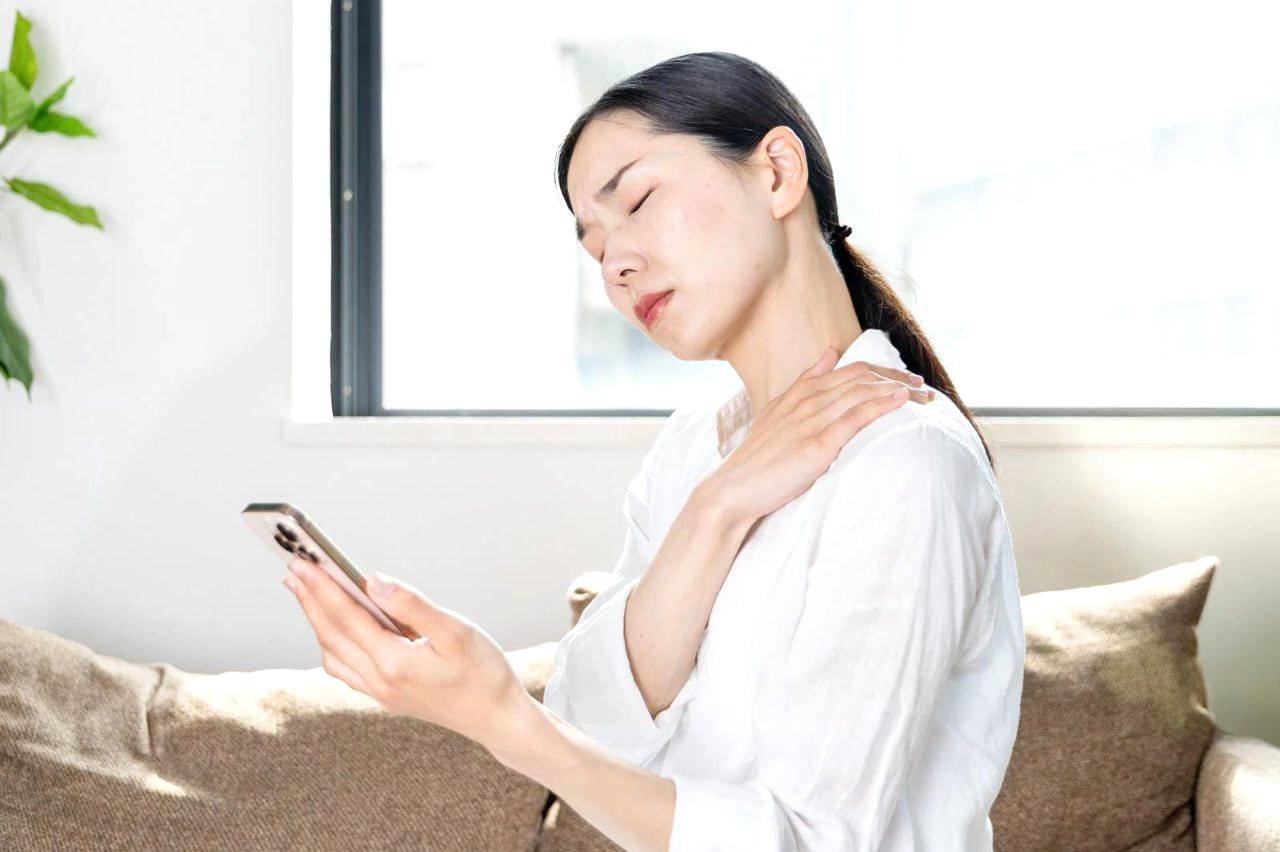 メガネを外してスマホを近づけるシニアの手と、注意を促す赤い禁止マーク