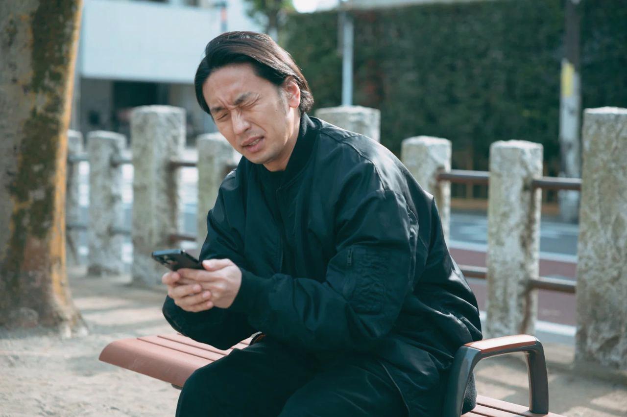 スマホのアプリストアでGeminiを検索し、インストールボタンを押している高齢者の男性の手元