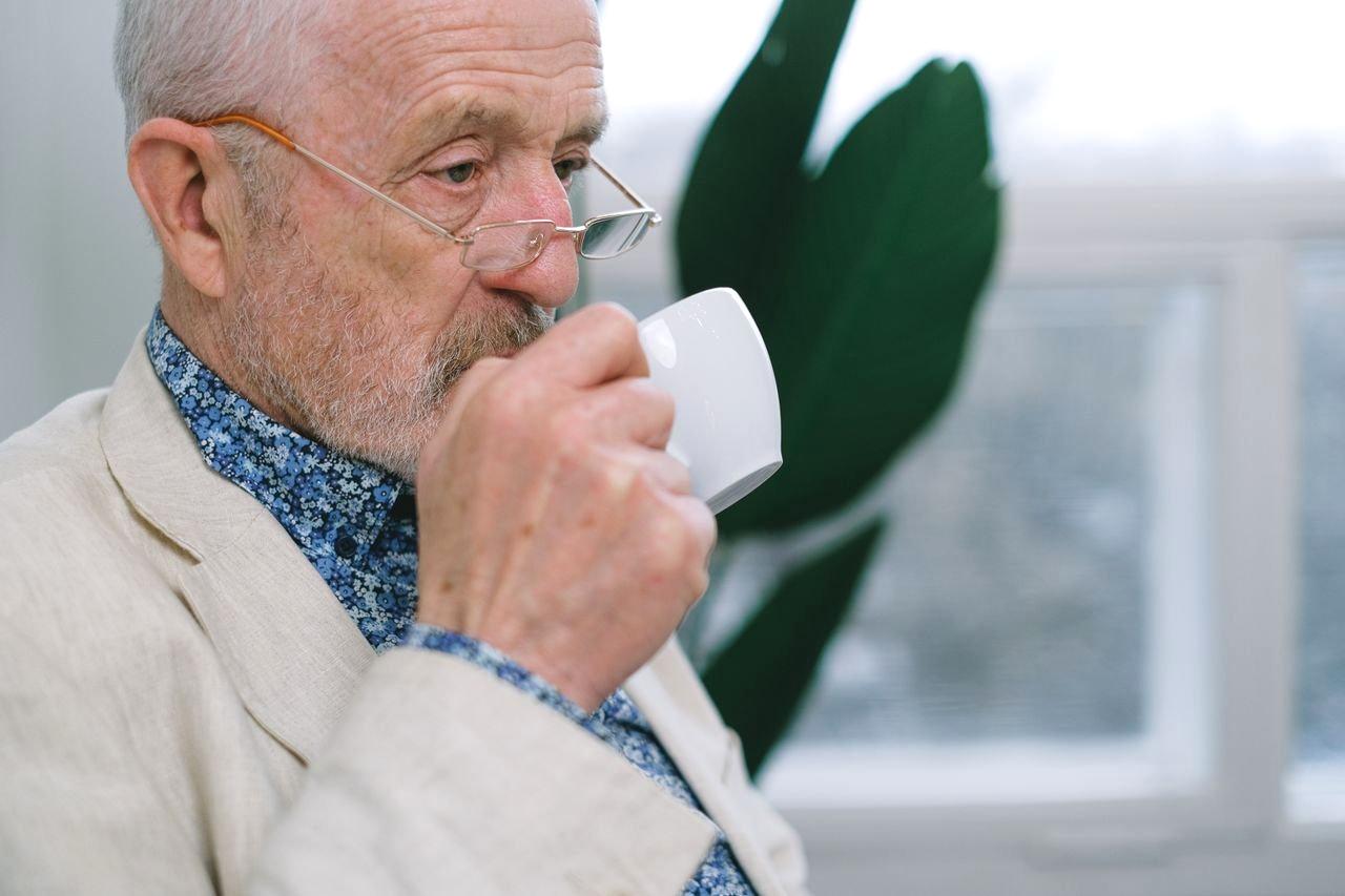 朝の洗面所で目元の違和感を気にする50代の人物をイメージした画像