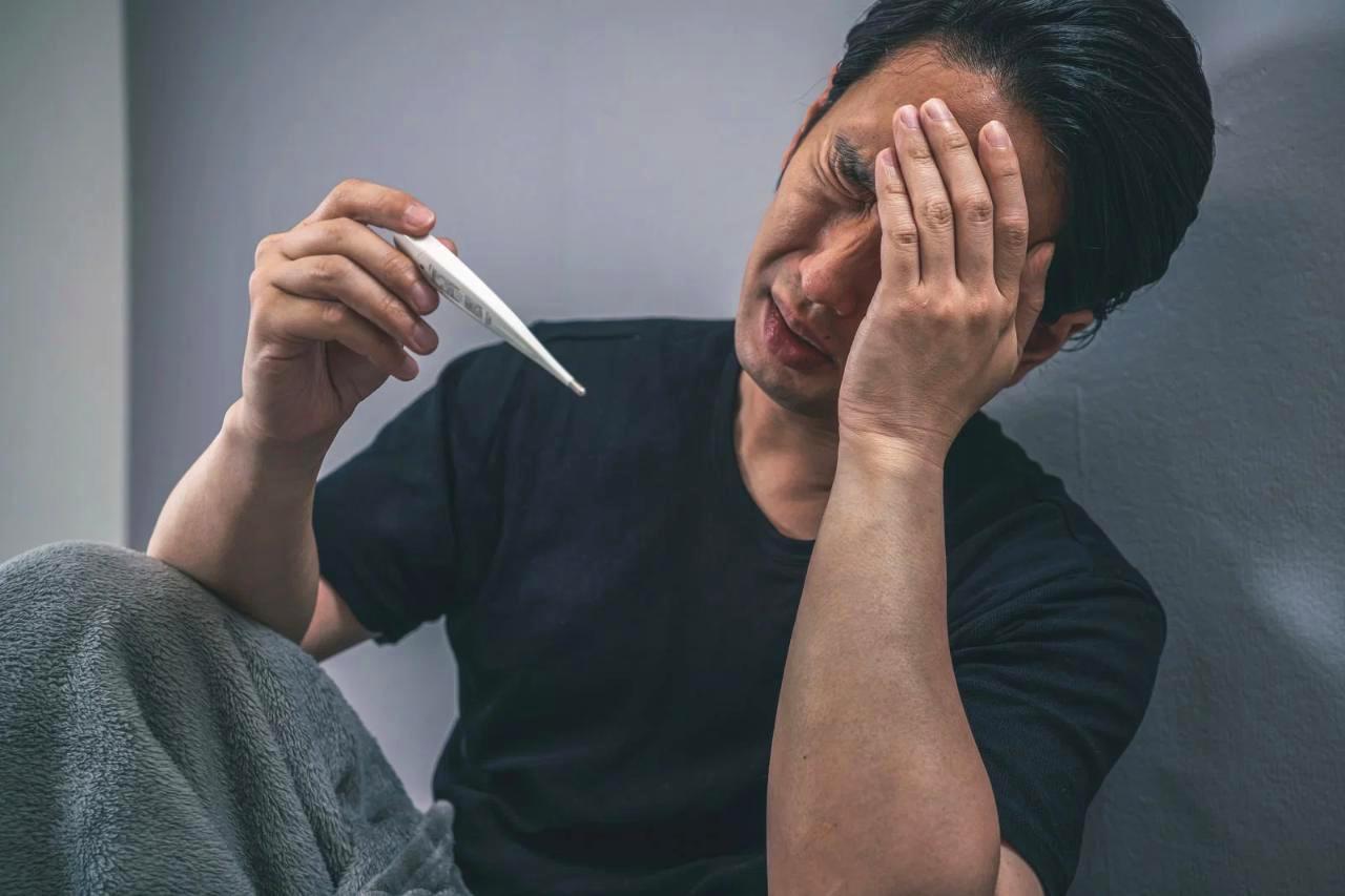 鼻水を飲み込む習慣を放置したことで体調不良を感じ、つらそうに喉をおさえる40代男性の様子