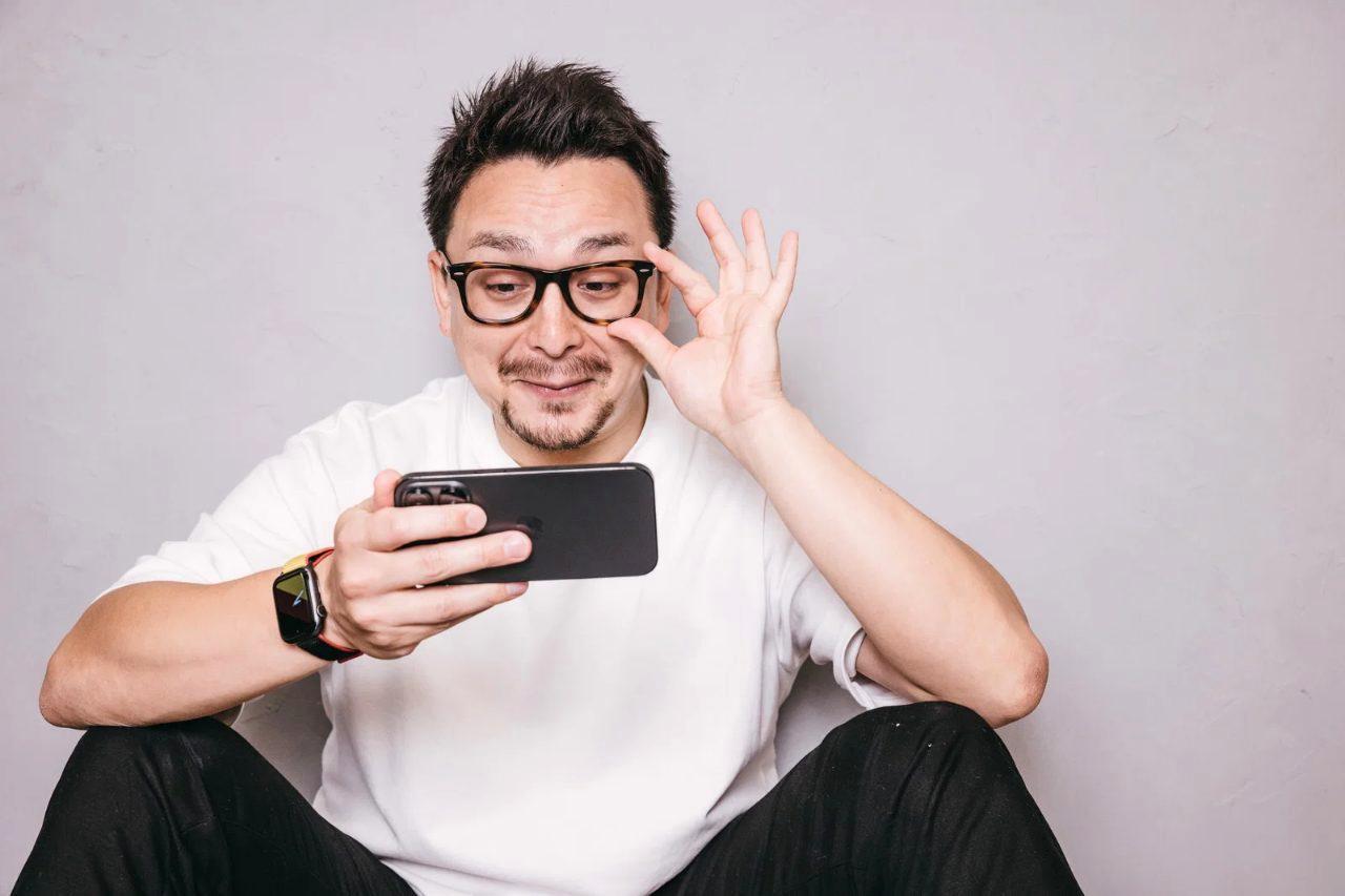 スマホを見ながら片手で玄関の床をサッと拭く女性の後ろ姿